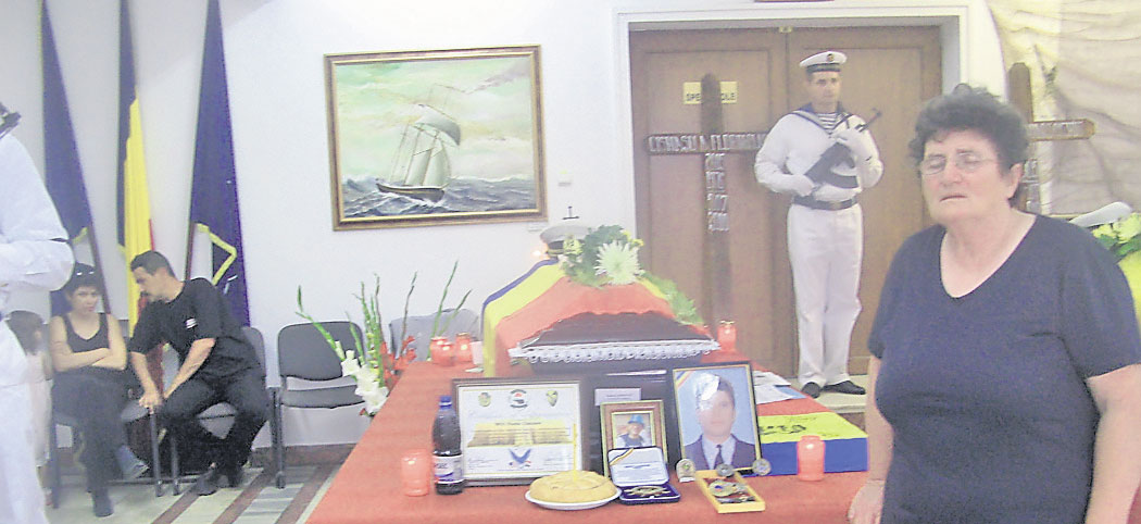 Maria Cişmaşu (dreapta), mama militarului, plânge lângă sicriul acoperit cu medalii ale fiului ei