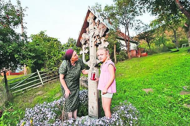 Tanti Eleonora îşi duce nepoţica să se roage la troiţa ridicată tot în curte